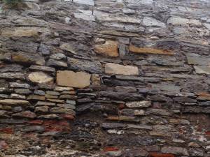 Древня каменная стена из разных материалов  со следами частого ремонта 