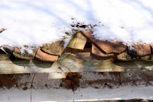Разрушенная старая черепичная  крыша под снегом (фрагмент) 