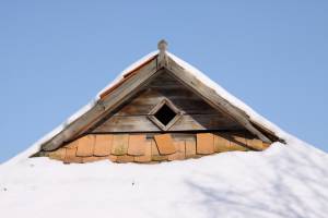 Старинная сельская крыша из черепицы под снегом 