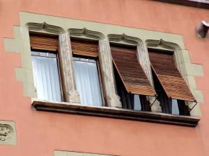 Широкое окно с колоннами и вертикальными ставнями  в старом доме 