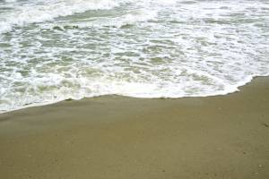 Волна смывает следы на песке