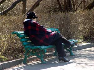 Женщина отдыхает в парке на лавочке 