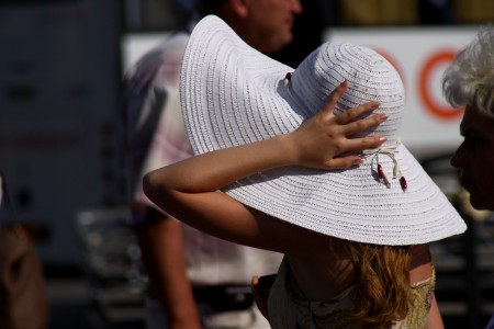Девушка придерживает рукой широкополую шляпу
