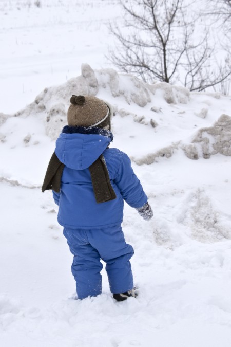 Ребенок гуляет по снегу.