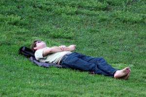 Мужчина лежит на траве босиком.